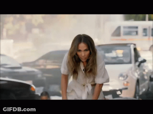 A Woman In A White Dress Is Bending Over In Front Of A Busy Street GIF