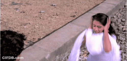 A Woman In A White Dress Is Covering Her Ears With Her Hands While A Man Looks On . GIF