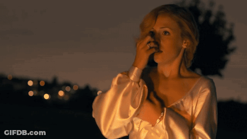 A Woman In A White Dress Is Covering Her Face With Her Hand GIF