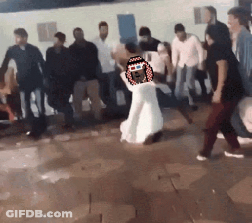 A Woman In A White Dress Is Dancing In A Crowd Of People GIF