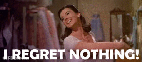A Woman In A White Dress Is Dancing In A Room With The Words `` I Regret Nothing '' Written Below Her . GIF