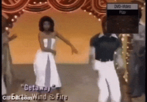A Woman In A White Dress Is Dancing In Front Of A Dvd Player That Says Dvd Video Play GIF