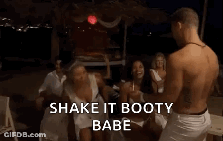 A Woman In A White Dress Is Dancing In Front Of A Group Of People And A Man . GIF