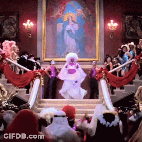 A Woman In A White Dress Is Dancing In Front Of A Large Painting GIF