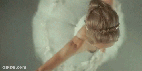 A Woman In A White Dress Is Dancing In The Water . GIF