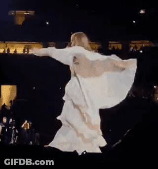 A Woman In A White Dress Is Dancing On A Stage With Her Wings Outstretched . GIF