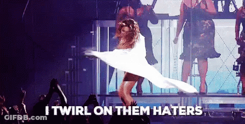 A Woman In A White Dress Is Dancing On A Stage With The Words I Twirl On Them Haters Written Below Her GIF