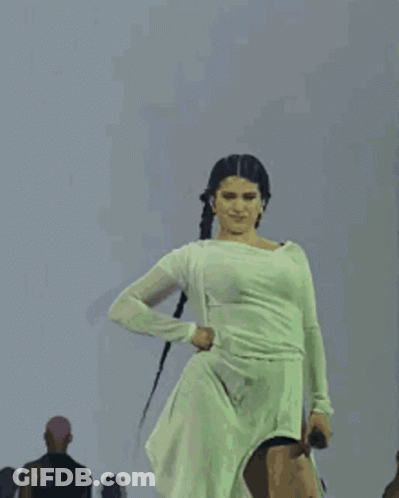 A Woman In A White Dress Is Dancing On Stage . GIF