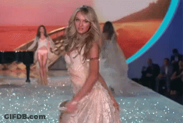 A Woman In A White Dress Is Dancing On The Runway GIF