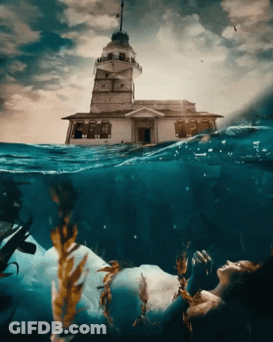 A Woman In A White Dress Is Floating In The Ocean GIF
