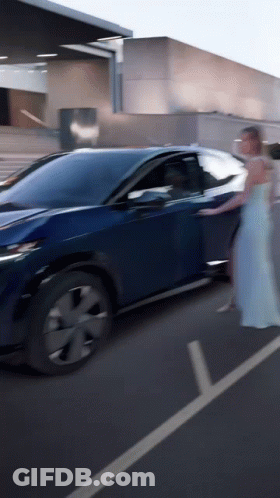 A Woman In A White Dress Is Getting Out Of A Car GIF