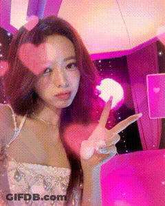 A Woman In A White Dress Is Giving A Peace Sign . GIF