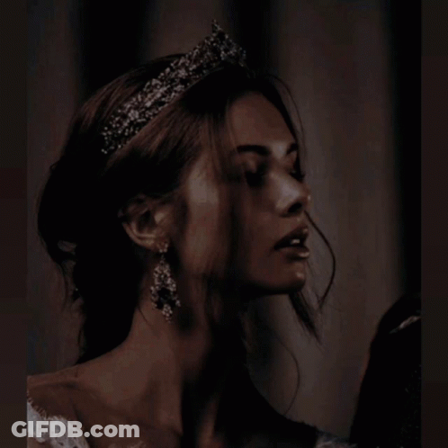 A Woman In A White Dress Is Holding A Candle In Her Hands GIF
