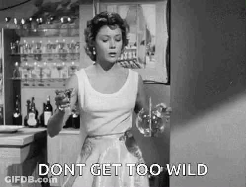 A Woman In A White Dress Is Holding A Glass Of Wine And A Glass Of Water . GIF