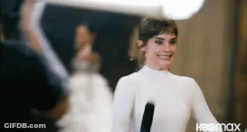 A Woman In A White Dress Is Holding A Microphone . GIF