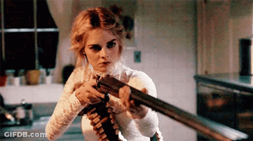 A Woman In A White Dress Is Holding A Shotgun In Her Hand . GIF