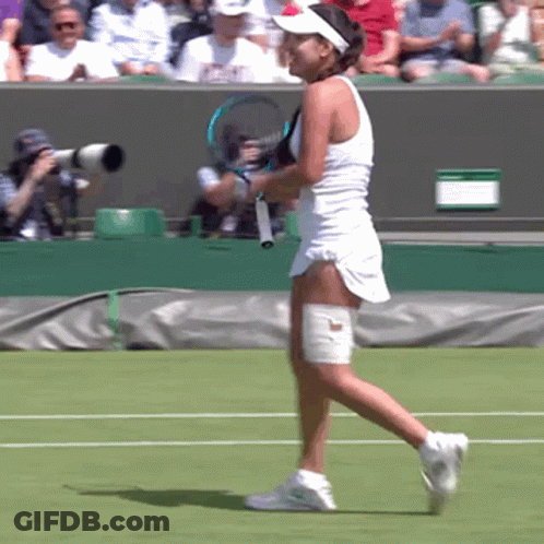A Woman In A White Dress Is Holding A Tennis Racket On A Tennis Court GIF