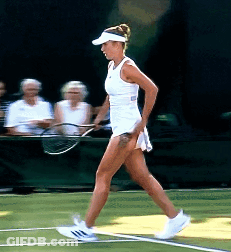 A Woman In A White Dress Is Holding A Tennis Racket On A Tennis Court GIF