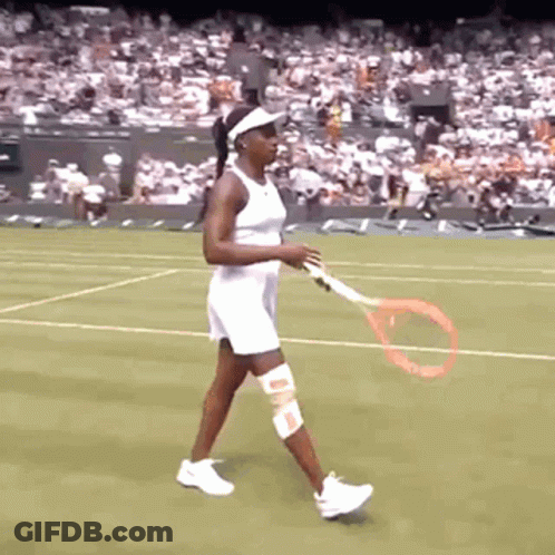 A Woman In A White Dress Is Holding A Tennis Racquet On A Tennis Court GIF
