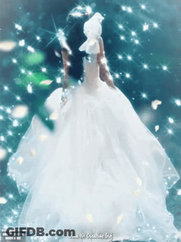 A Woman In A White Dress Is Holding A White Dove In Her Hand GIF
