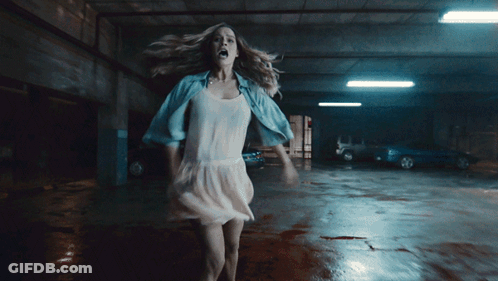 A Woman In A White Dress Is In A Parking Garage GIF