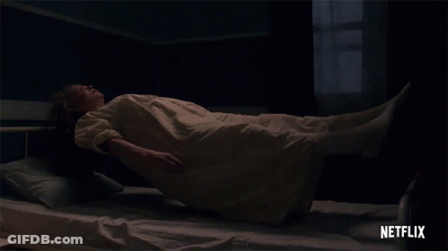 A Woman In A White Dress Is Laying On A Bed With A Netflix Logo Behind Her GIF
