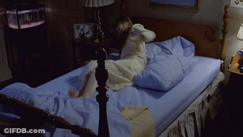 A Woman In A White Dress Is Laying On A Bed GIF