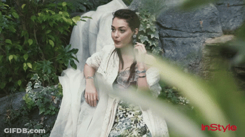 A Woman In A White Dress Is Laying On A Rock With Instyle Written On The Bottom Left GIF