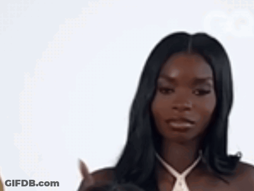 A Woman In A White Dress Is Pointing At Something . GIF
