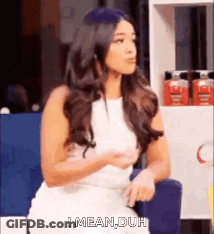 A Woman In A White Dress Is Sitting In A Chair And Talking To Someone . GIF