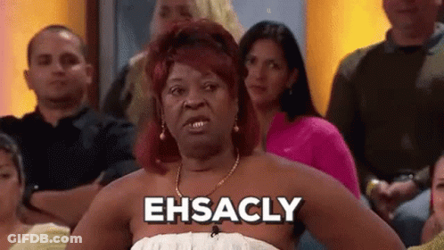 A Woman In A White Dress Is Sitting In A Crowd Of People And Saying Ehsacly . GIF