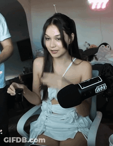 A Woman In A White Dress Is Sitting In Front Of A Microphone That Says Tnt On It GIF