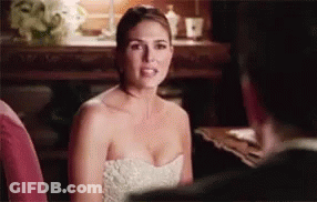 A Woman In A White Dress Is Sitting Next To A Man In A Suit . GIF