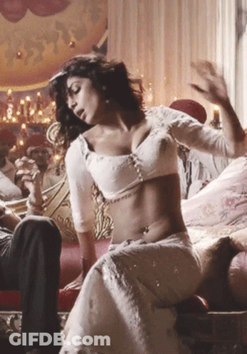 A Woman In A White Dress Is Sitting On A Couch GIF