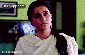 A Woman In A White Dress Is Sitting On A Couch In A Living Room . GIF