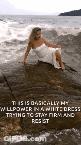 A Woman In A White Dress Is Sitting On A Rock In The Water . GIF