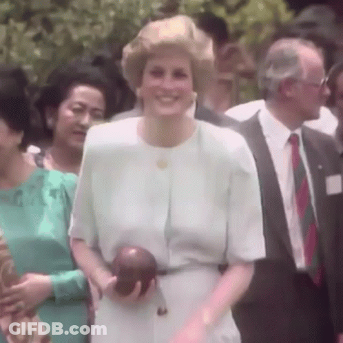 A Woman In A White Dress Is Smiling While Holding An Apple GIF