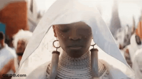 A Woman In A White Dress Is Standing In A Crowd Of People . GIF