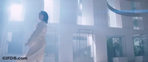 A Woman In A White Dress Is Standing In A Room With A Lot Of Windows . GIF