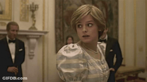 A Woman In A White Dress Is Standing In A Room With A Man In A Tuxedo . GIF