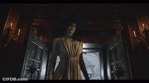 A Woman In A White Dress Is Standing In A Room With Candles . GIF