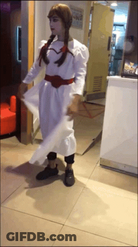 A Woman In A White Dress Is Standing In Front Of A Counter GIF