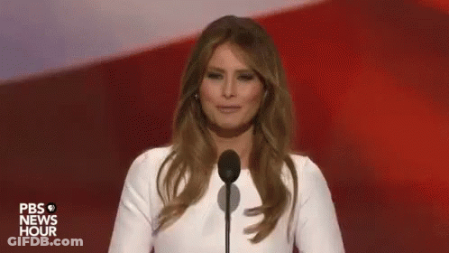 A Woman In A White Dress Is Standing In Front Of A Microphone On A Stage . GIF