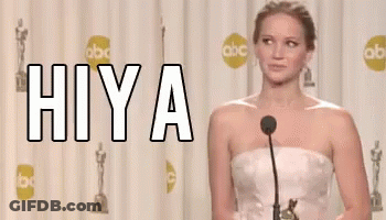 A Woman In A White Dress Is Standing In Front Of A Microphone With The Word Hiya Written On It GIF