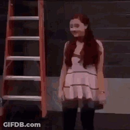 A Woman In A White Dress Is Standing In Front Of A Red Ladder . GIF