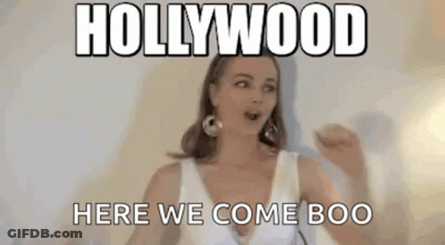 A Woman In A White Dress Is Standing In Front Of A Wall With A Meme . GIF