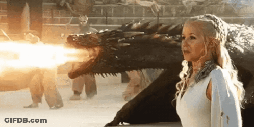 A Woman In A White Dress Is Standing Next To A Dragon That Is Shooting Fire . GIF
