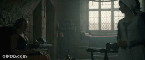 A Woman In A White Dress Is Standing Next To A Man In A Black Shirt GIF