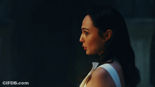 A Woman In A White Dress Is Standing Next To A Man In A Dark Room . GIF