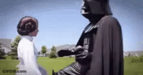 A Woman In A White Dress Is Standing Next To A Statue Of Darth Vader . GIF